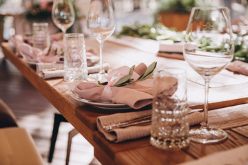wooden banquet tables decorated with floral arrangements, on the tables are plates, glasses and candles