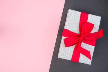 Pink and black paper texture, silver glitter gift box with red ribbon on it, background for template, horizontal, copy space