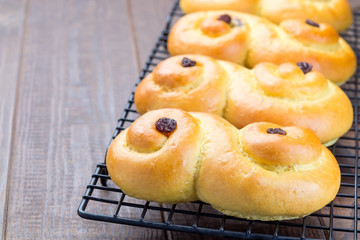 Swedish and scandinavian Christmas saffron buns Lussekatter on cooling tray, brown wooden background, horizontal, copy space