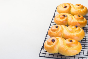 Swedish and scandinavian Christmas saffron buns Lussekatter on cooling tray, light gray concrete background, horizontal, copy space