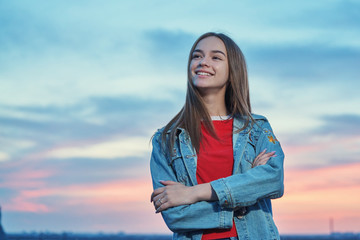 Teen girl standing looking to the sky at sunset background