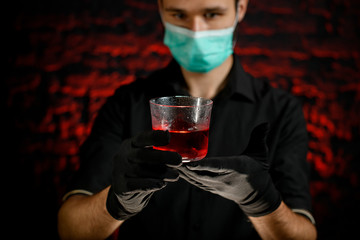 Barman presents glass with cold alcoholic cocktail.
