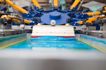 Silk screen printing. Serigraphy. Color paints and fabric. Plastisol paint and squeegee.