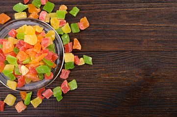 candied fruit in a glass plate on a wooden background