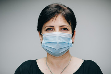 Woman Wearing Medical Mask During Coronavirus COVID-19 Epidemic. Sick woman wearing protection during pandemic. Pretty Caucasian Woman Taking on Medical Mask