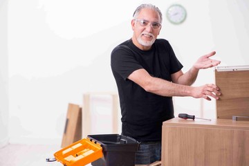 Old male carpenter working indoors