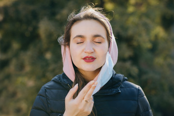 Girl Takes Off Medical Mask Isolated on sunset background. Breathes deeply and smiling looking at...