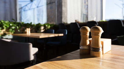 Close up of salt and pepper on wooden table in modern restaurant