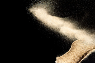 Brown colored sand splash.Dry river sand explosion isolated on black background. Abstract sand...