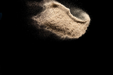 Brown colored sand splash.Dry river sand explosion isolated on black background. Abstract sand...