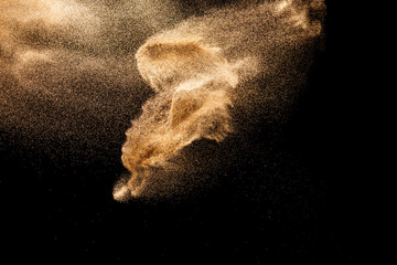 Brown colored sand splash.Dry river sand explosion isolated on black background. Abstract sand...