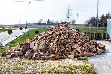 A firewood stacked in a pile, lying on the property near the metal garage, wooden background.