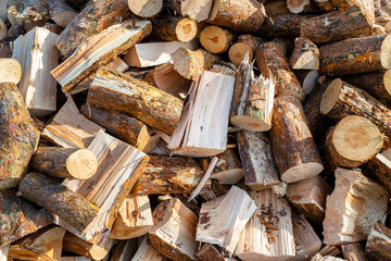 A firewood stacked in a pile, lying in the sun, close up shot, wooden background.