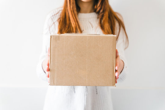 Young woman received the delivery of a cardboard package from a courier - Millennial buys products online - Copy space