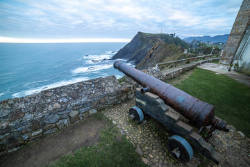 amazing landscape from a field of a cannon on the foreground and mountains and the sea on the background in the north of spin at the coast