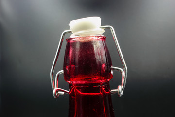 red glass bottle with stopper isolated on a black background