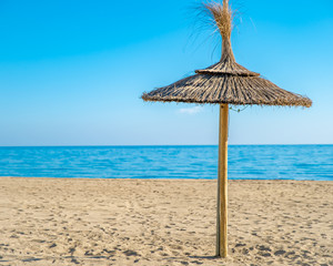 Straw umbrella on sea beach, blue sky