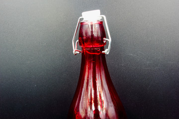 red glass bottle with stopper isolated on a black background