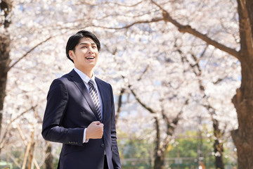 桜を背景に笑顔で立つ日本人男性ビジネスマン