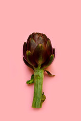 Fototapeta premium fresh artichokes on a pink background. layout top view. concept of seasonal vegetables. delivery of fresh vegetables