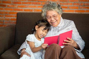 Closeup photo of Grandmother teaches to read a book her granddaughter,Family concept.