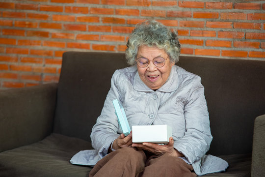 Portrait of happy senior woman holding gift box,Senior woman opening gift.