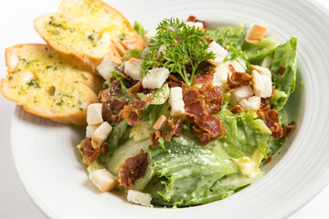 caesar salad serve with garlic bread serve in white plate close up shot