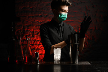 barman in medical mask puts on black gloves