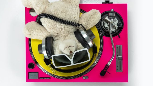 a dj teddy bear lying on turntables