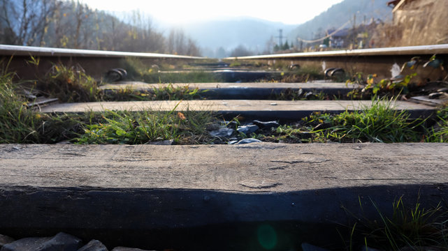 Close Up perspective view of railway tracks on a bright sunny day. Rails and wooden sleepers in oil with crushed stone. low down view of railway train transport metal steel rails.