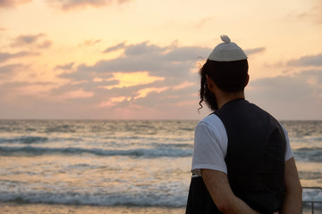 Silhouette of a religious Jewish man contemplating by the ocean