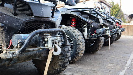 Many parked ATVs on a dirt road, close up. four-wheel car, all-terrain vehicle. large wheels with powerful legs. Mountain tour in the Carpathians © Yevhen Roshchyn