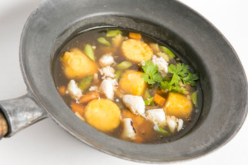 seafood sticky soup with tofu and vegetables serve in black bowl