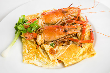 luxury stri fried thai noodle padthai noodle wrapped in omelet top with big prawn shrimps serve in white plate