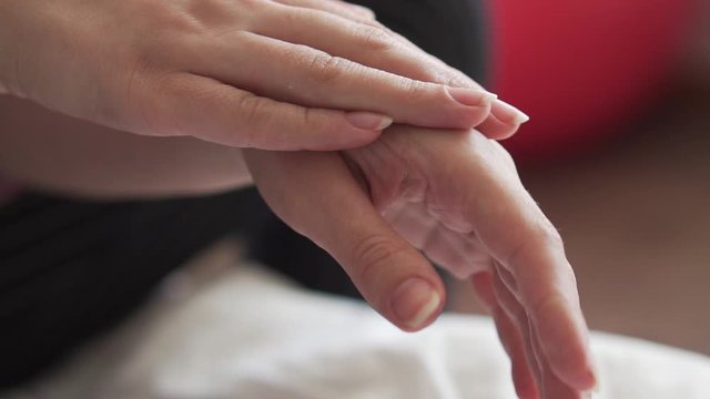 Clean well-groomed hands of a young woman applying hand cream