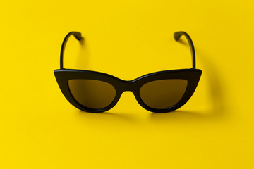 Fashionable sunglasses on a yellow background.