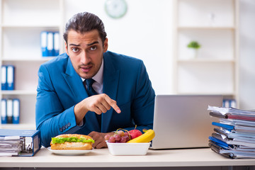 Young male employee having breakfast at workplace