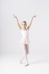 Adorable pre-teen ballerina dancing on white background