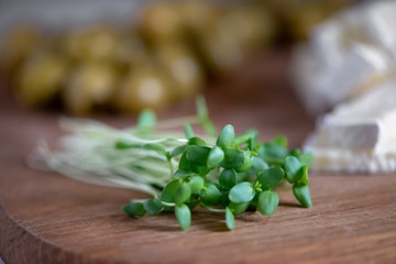 microgreen on a wooden board, in the background olives and feta cheese