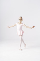 Adorable pre-teen ballerina dancing on white background