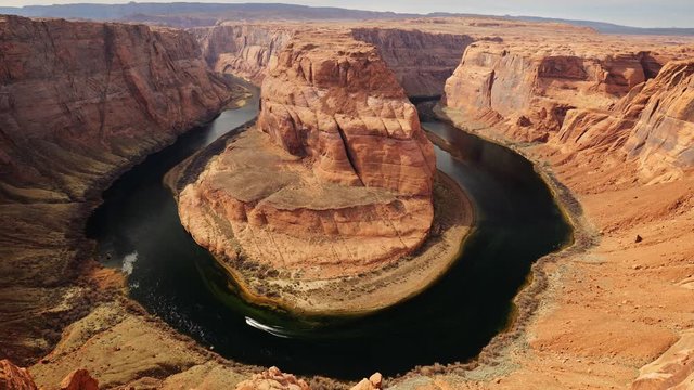 Zoom out shot of Horseshoe Bend. Motor boat moves along Colorado river