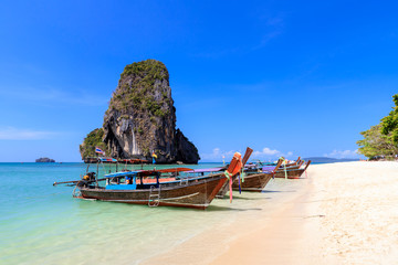 Long tail boat and turquoise crystal clear sea water with limestone cliff and mountain at Phra Nang Beach, Krabi, Thailand