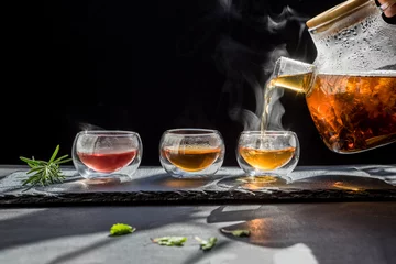 Schilderijen op glas Kopje hete thee rietsuiker droge theeblaadjes, hete thee in glazen beker met stoom en citroen. warm eten en gezond maaltijdconcept © lesterman