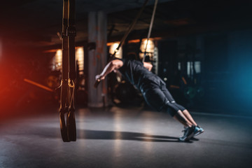 Naklejka na ściany i meble young man has crossfit workout with trx in modern gym