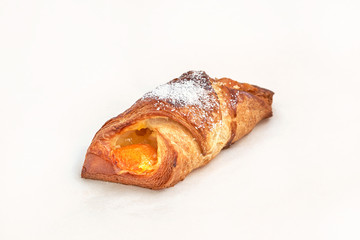 A puff pastry with apricot jam. Closeup on a light background