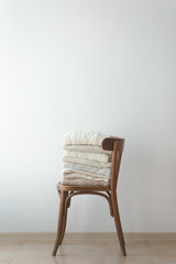 Stock Photo - Stack of cozy knitted sweaters on a wooden chair