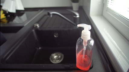 Pump bottle of hand sanitizer placed in kitchen sink. Kill germs, viruses and bacteria