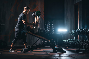 young man has workout with personal trainer in modern gym