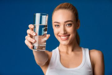 Girl Offering Glass Of Water To Camera Over Blue Background