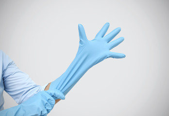 Female shoulder putting on sterile gloves. Hand woman wearing gloves on grey background.